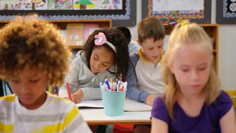 front view of mixed-race schoolkids drawing on notebook in the classroom 4k