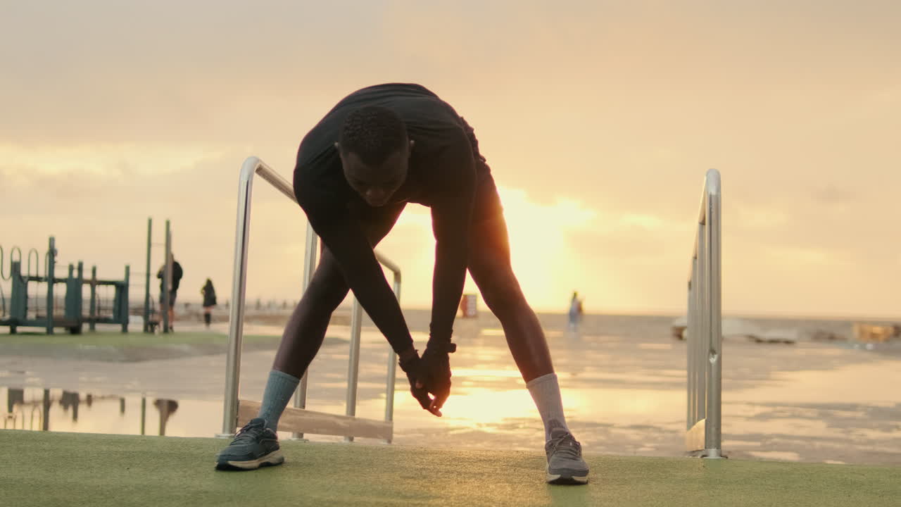 Young Man Stretching Outdoors on Sports Ground at Sunset