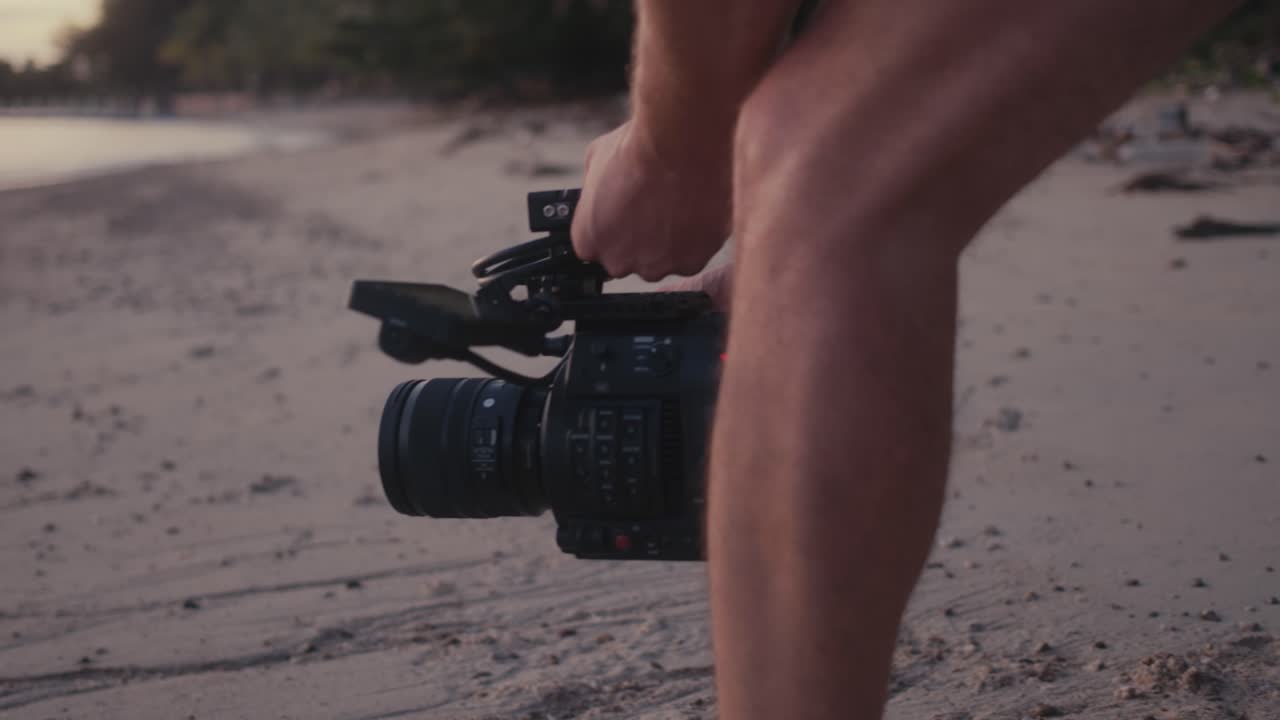 Person filmer video på en strand ved solnedgang.
