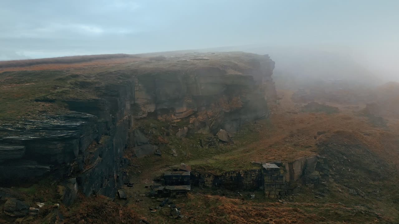 vista aérea alta en las nubes, niebla moviéndose sobre las cimas de los acantilados, colinas doradas nubladas y hermosos afloramientos rocosos y páramos