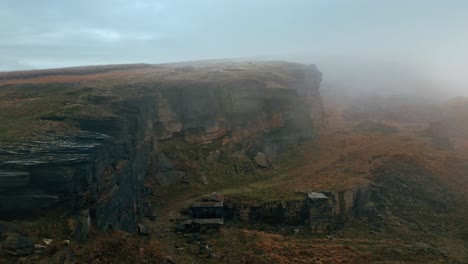 high up aerial view in the clouds, mist moving in over the cliff tops, foggy golden hills and beautiful rocky outcrop and moorlands