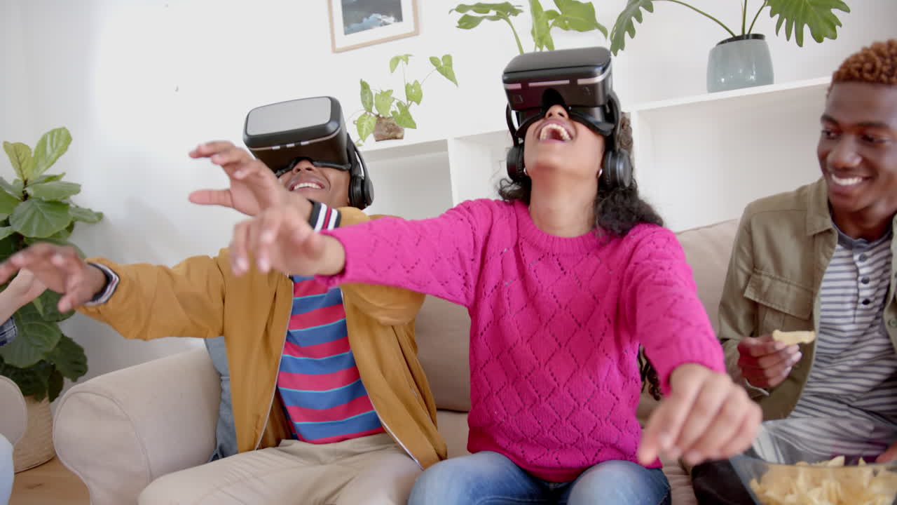 grupo diverso de amigos adolescentes felices con bocadillos jugando con auriculares vr en casa, cámara lenta