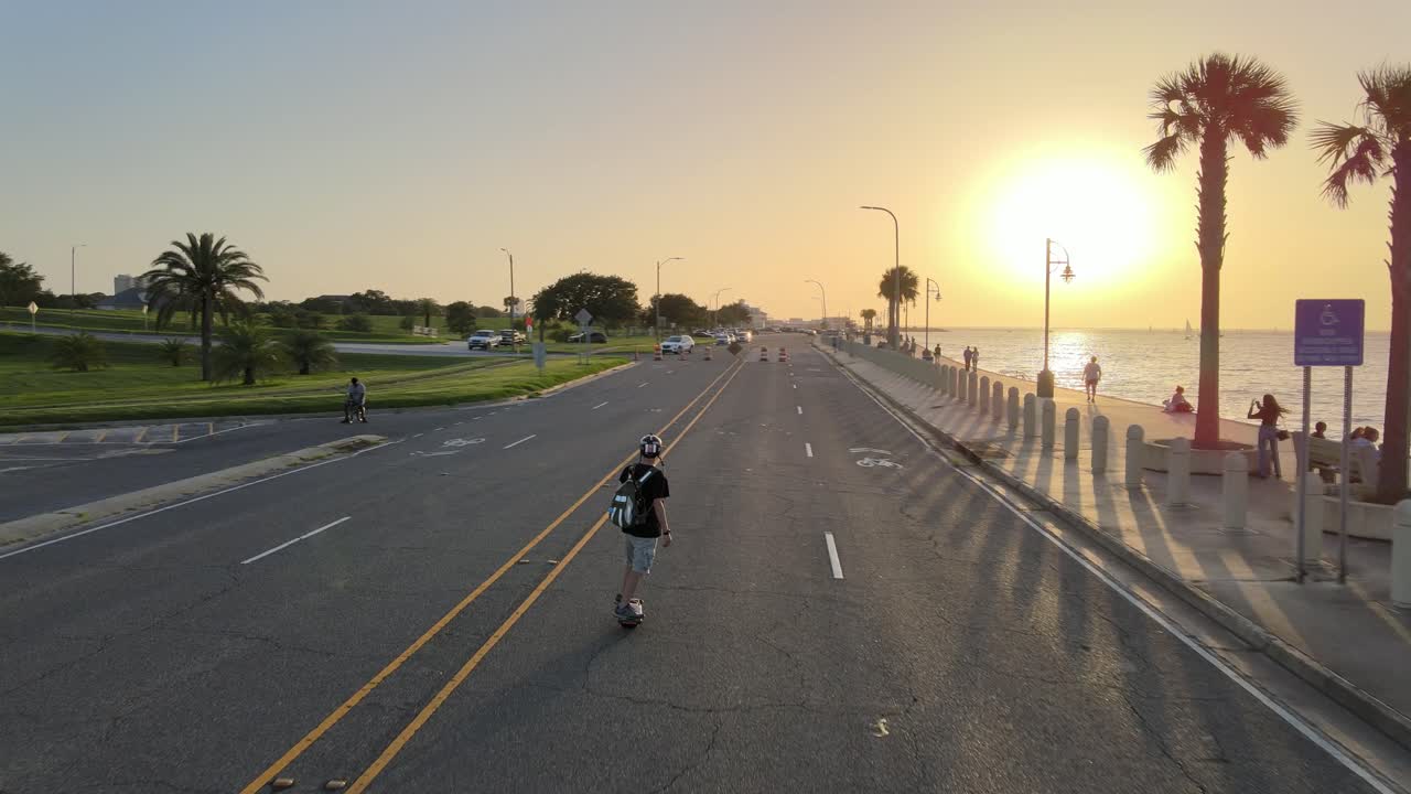 Young Man Leisurely Strolling At Lakeshore Drive During A Beautiful Sunset. - aerial, follow
