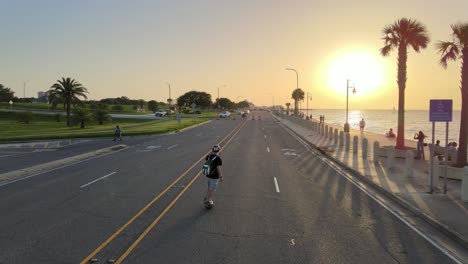 young man leisurely strolling at lakeshore drive during a beautiful sunset. - aerial, follow