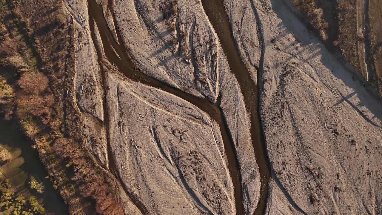 Aerial top down of Wanaka River at golden sunset. Dried out stream in New Zealand. Ecological calamities and mud