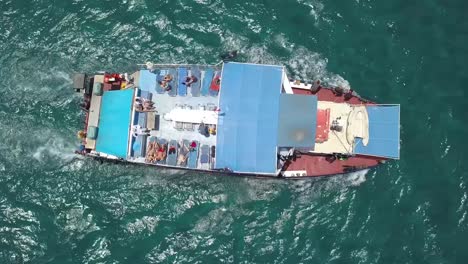 fotografía cenital de personas disfrutando del sol relajándose en un gran barco azul, chipre