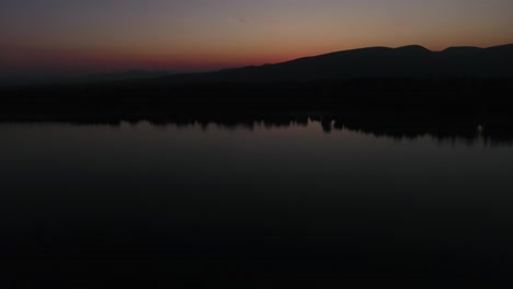 tilt up shot of sunrise or sunset view with reflection on the water and mountains in the background