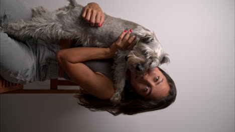 vertical slow motion of a beautiful brunette latin model carrying her schnauzer dog and kissing it