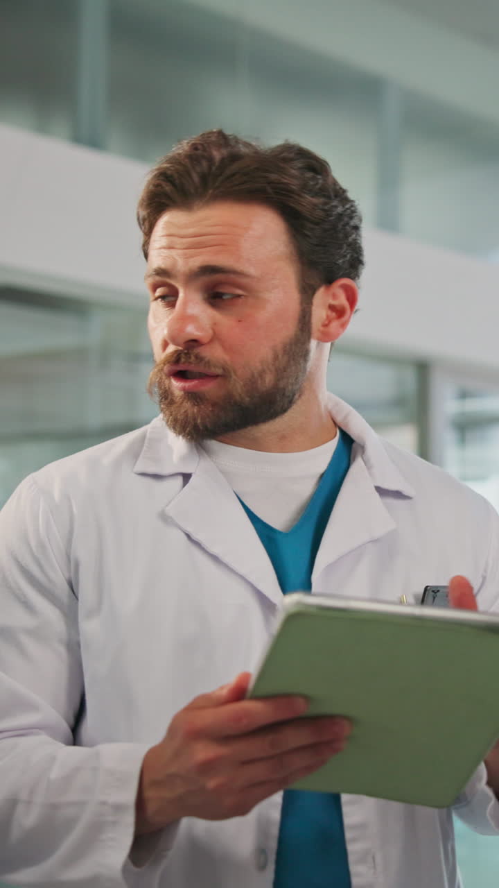 Medico uomo in camice che parla e utilizza un tablet digitale