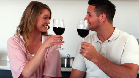 una pareja feliz con vino rojo en la cocina