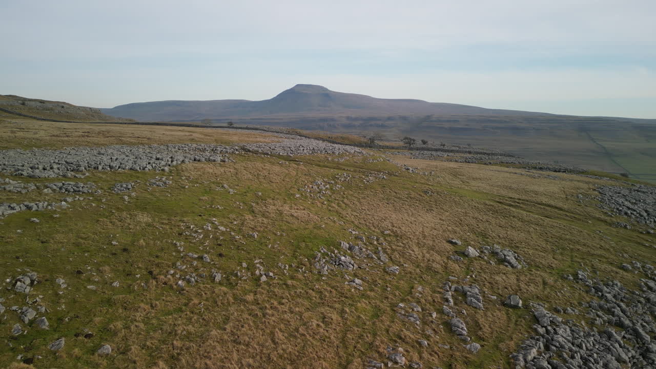 páramos de colinas rocosas se elevan revelando la montaña ingleborough en el horizonte en la campiña inglesa yorkshire reino unido