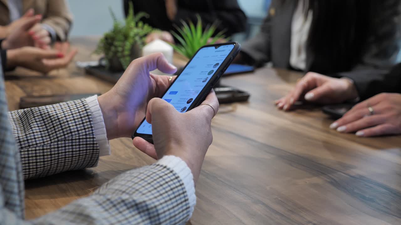 empresaria revisando información en el teléfono inteligente y compartiéndola con su equipo en la reunión