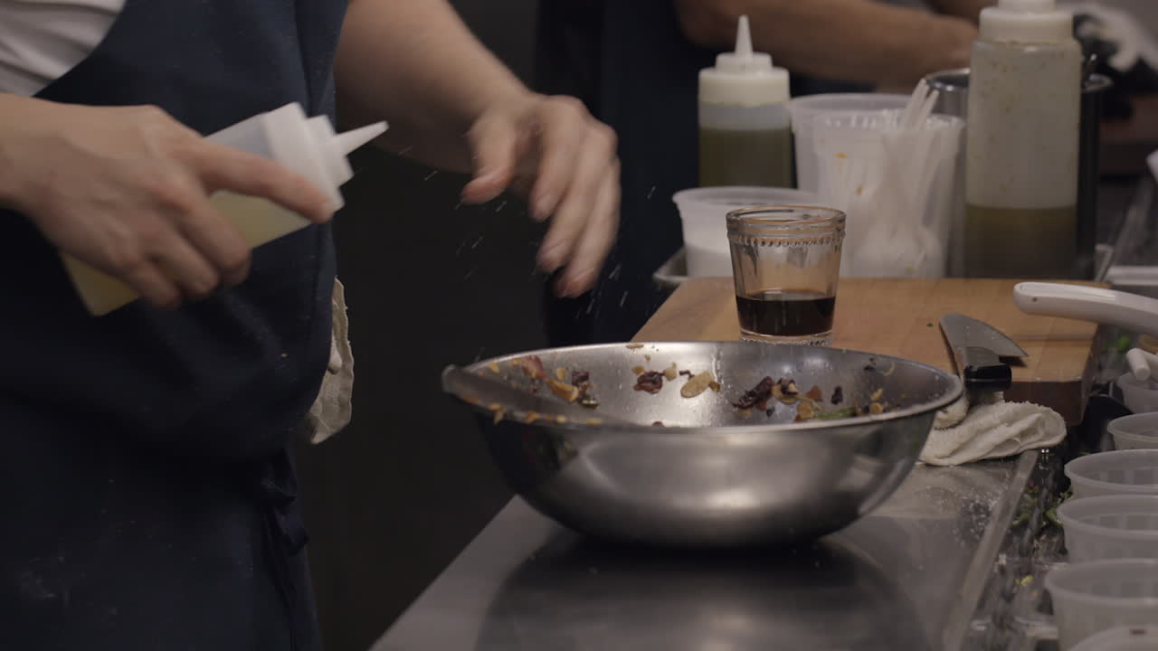 повар на кухне ресторана готовит салат в серебряной миске