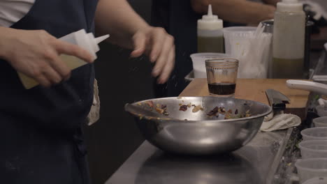 a cook in a restaurant kitchen makes a salad in a silver bowl