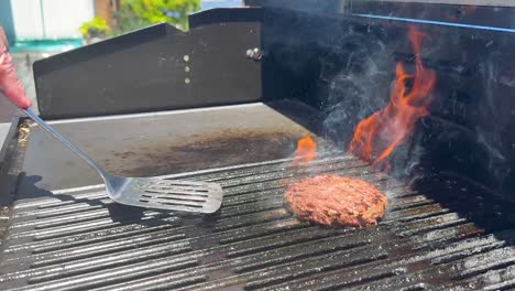 flipping burger patty with flames and smoke