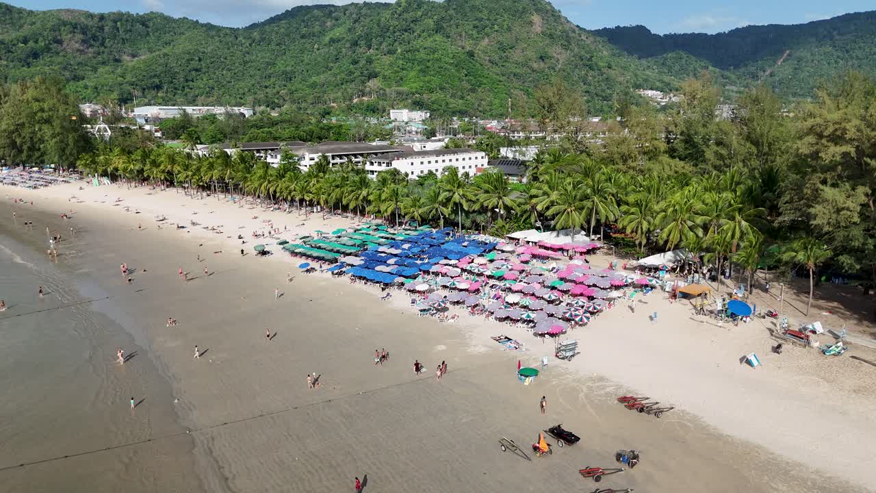 드론 영상은 푸켓 해변의 은 날에 활기찬 우산과 해변을 찾는 사람들을 포착하여 활기찬 열대 분위기를 보여줍니다.