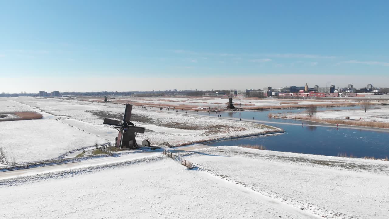 pólderes holandeses de invierno nevado, gente patinando sobre hielo en el canal al lado del molino de viento, antena