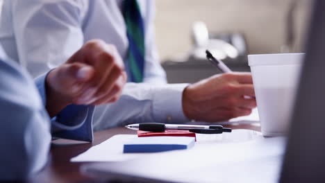 close up of man and woman making notes in a business meeting