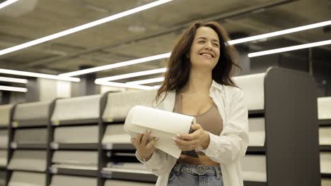 A Customer Carefully Checks the Selection of Wallpaper in an Interior Renovation Store