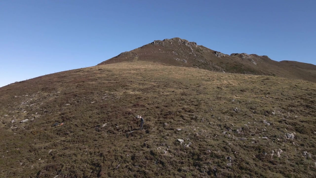 Vista aerea di un escursionista solitario su una collina erbosa nel Cantal, Francia, catturata da un drone.