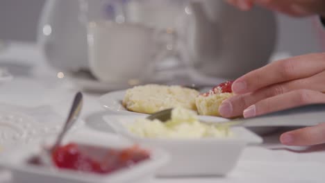 close up shot of person with traditional british afternoon tea with scones cream and jam 6