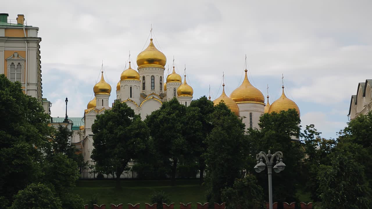 величественный храм с золотыми куполами слегка скрыт за деревьями. камера снимает в движении. красивые кадры архитектуры