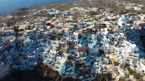 luftflug in richtung des berühmten griechischen dorfes oia mit weißen höhlenhäusern und villen in santorini, griechenland