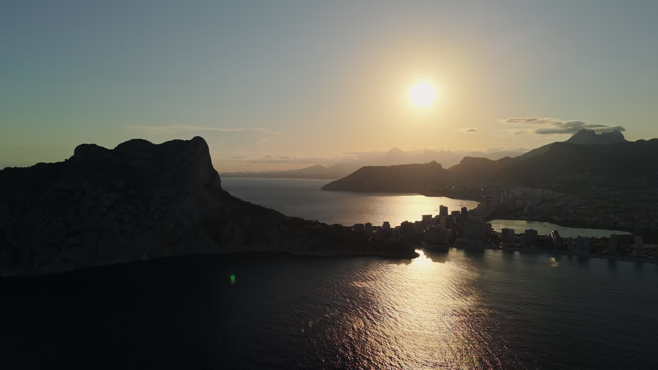 Vista Aérea Panorâmica de Cidade Costeira e Montanha ao Pôr do Sol.