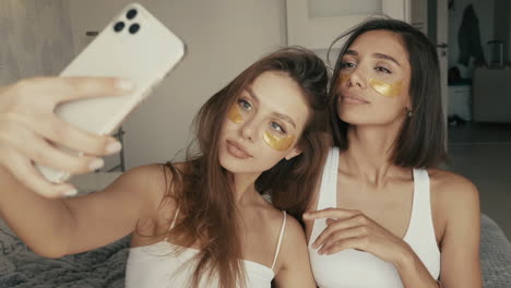 two women taking a selfie with gold eye patches