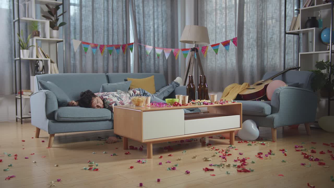 술에 취한 아시아인 남자가 집에서 파티를 축하한 후 소파에서 잠을 자고 있다