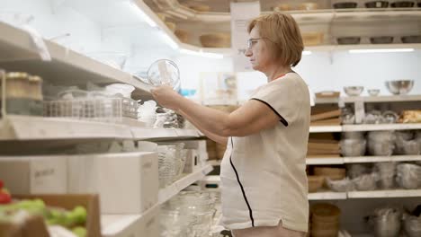 mujer mayor comprando platos en una tienda de artículos para el hogar