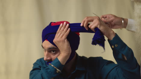 Studio-Shot-Of-Senior-Sikh-Man-Helping-Younger-Sikh-Man-To-Tie-Fabric-For-Turban-Against-Plain-Background-Shot-In-Real-Time-4