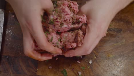 mashing ground beef on wooden cut board