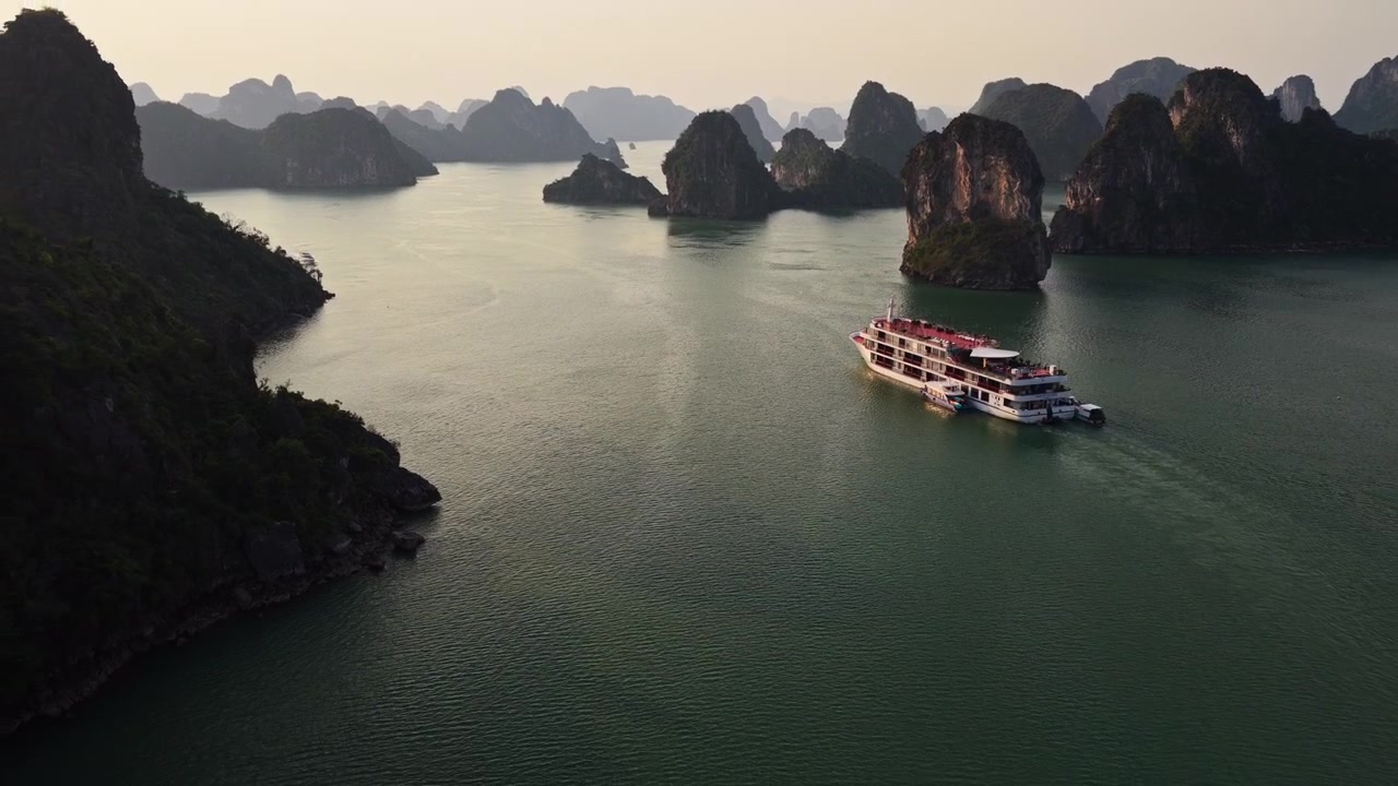 Vịnh Hạ Long Việt Nam: Cảnh quay từ trên cao lùi dần du thuyền sang trọng đi qua những ngọn núi đá vôi và hòn đảo xanh