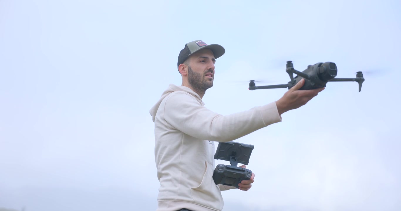 Bir Adam, Havadan Fotoğraf ve Video Çekimi İçin Uzaktan Kumandalı Ekipman Kullanarak Bir DJI Mavic 4 Pro Drone'u İşletiyor. Yakın Orta Çekim