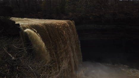 wide shot of a swift current dropping over balls falls with tilt down to the misty river below