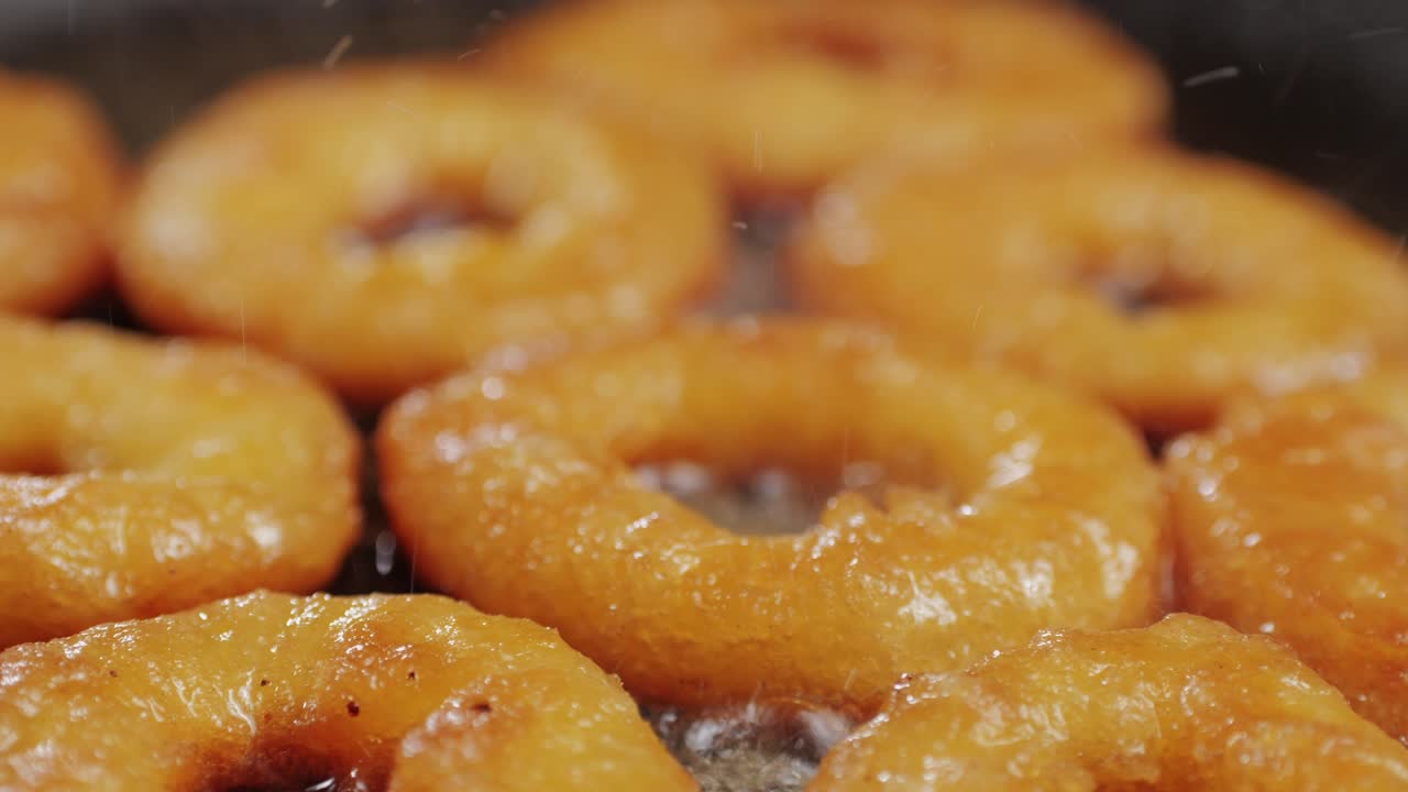 Fried crispy onion rings in a frying pan with oil close-up macro. Roasted onion rings for snacks at bar, cafe. Fast food. Delivery. Beer snacks