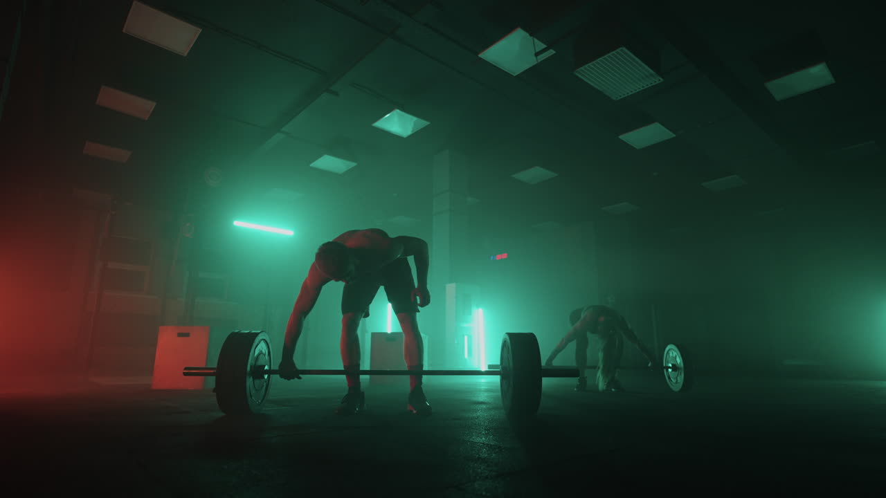 잘생긴 남자와 섹시한 여자가 체육관에서 훈련하고 있습니다. 바벨을 들어올리며 체력과 힘을 키우고 있습니다.