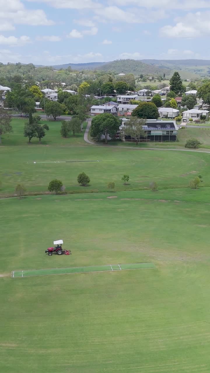 트랙터 가 큰 초록색 스포츠 경기장을 고 있다