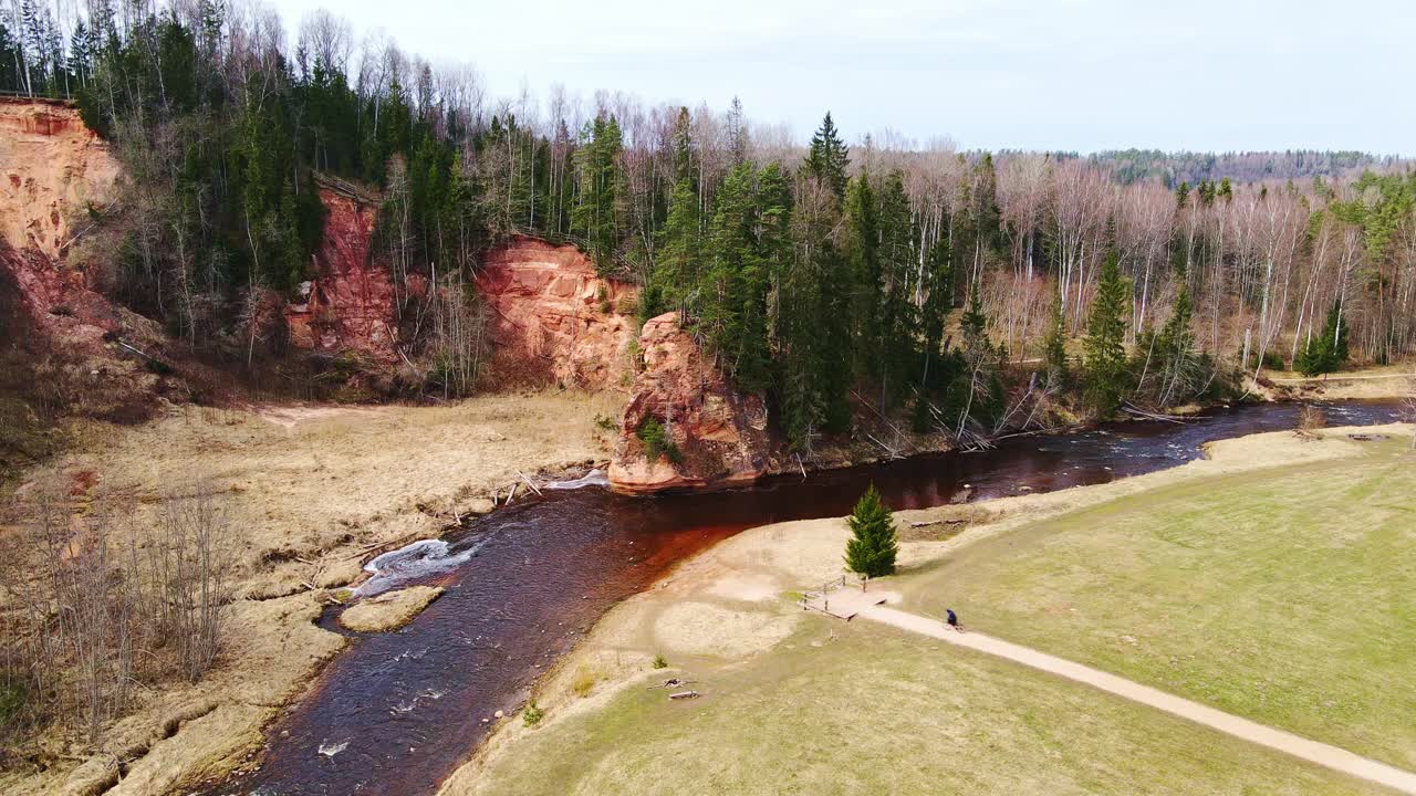 Cyclist approaching Zvārtes Rock, peaceful Latvian nature, Amata river, spring