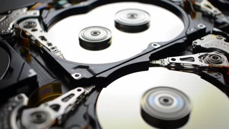 a close view reveals the internal components of computer hard drives, showcasing the spinning disks, read/write heads, and intricate engineering.