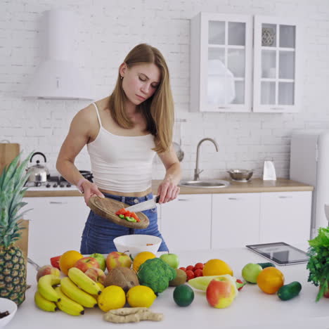 young pretty woman preparing tasty salad on the modern kitchen. lots of fresh organic ingredients on the table indoors. healthy food. dieting concept.