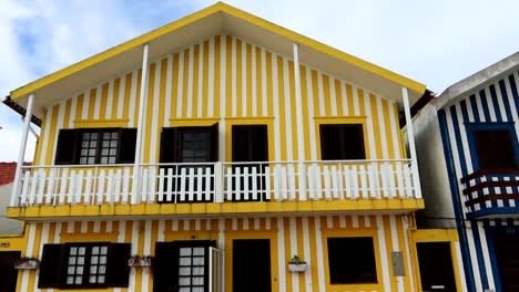 Iconic-two-story-house-painted-with-white-and-yellow-stripes-at-Costa-Nova-Beach