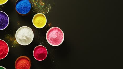 video of multi coloured powder in bowls with copy space on black background