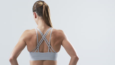 joven atleta mujer caucásica en traje de fitness sobre un fondo blanco