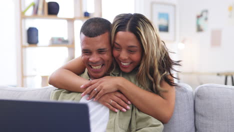 computadora portátil, abrazo y pareja feliz en el sofá en casa