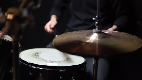 musician playing drums in a dark room