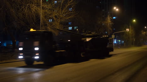 military tank and other vehicles at night in a city