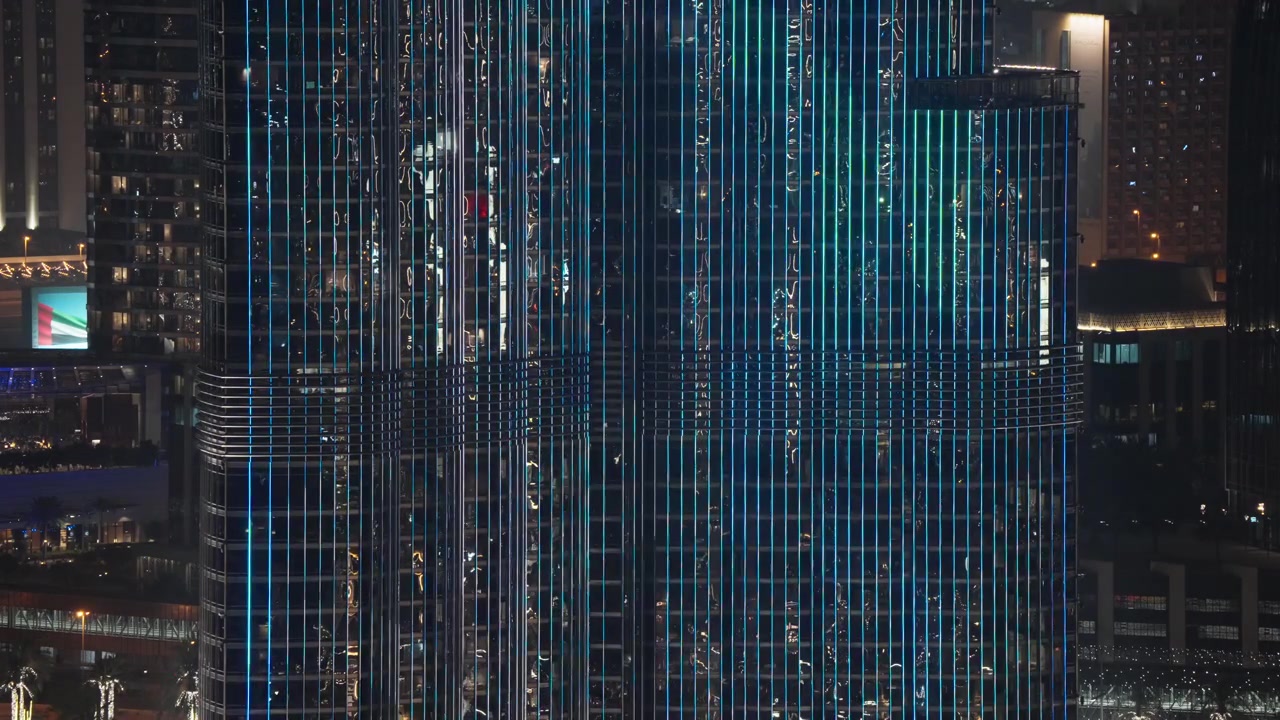 Oplyst skyskraberfacade med dynamiske LED-lysmønstre om natten.