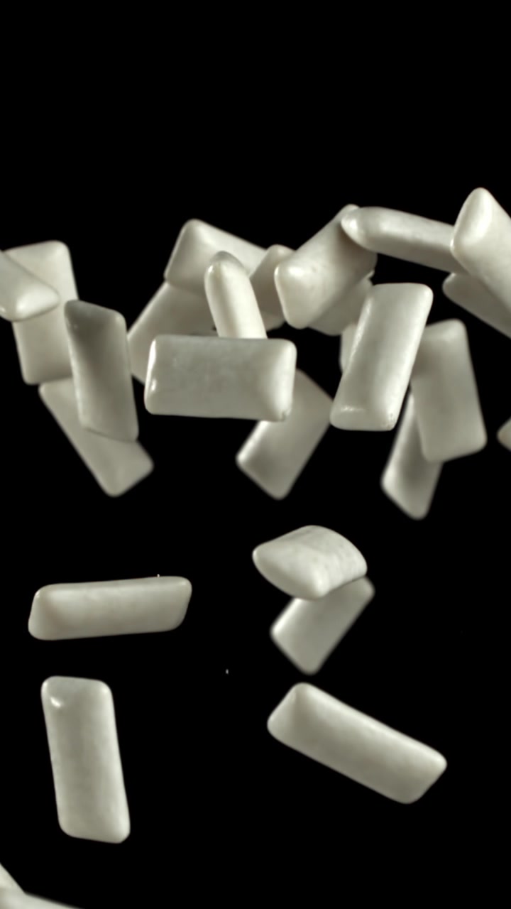 Pezzi di gomma da masticare bianca che cadono e galleggiano su sfondo nero